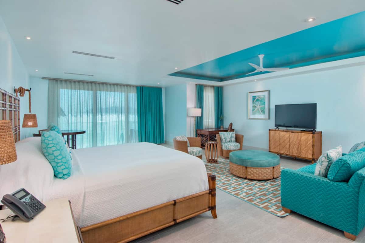A modern hotel room with a large bed, a sofa, a desk, and a television.