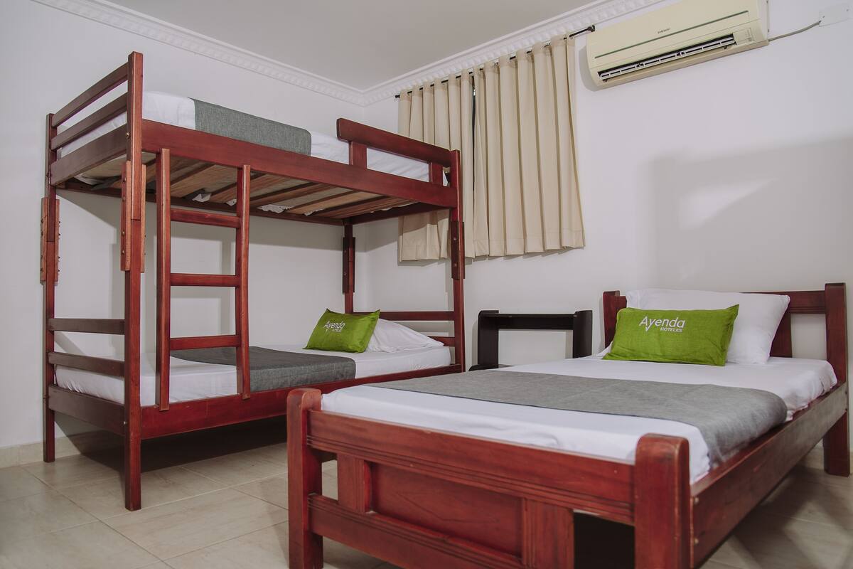 Ein Zimmer mit zwei Etagenbetten und einem Einzelbett, jeweils mit Kissen und Decken.