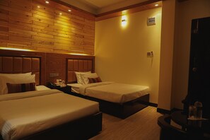 Habitación de hotel con dos camas, paneles de madera en las paredes y una mesita con lámpara.