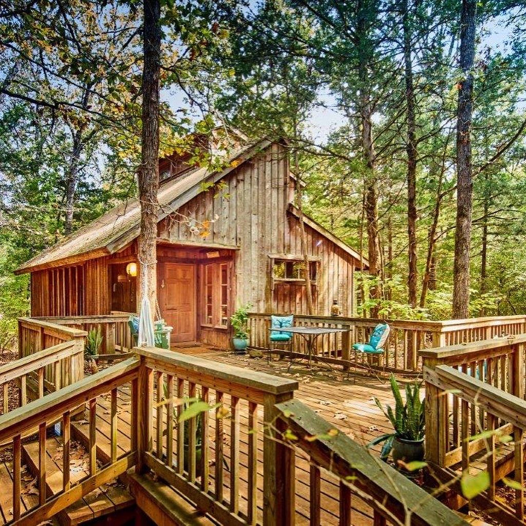 Un chalet rustique doté d’une terrasse en bois, entouré d’arbres.