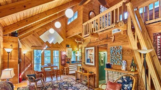 L’intérieur d’un chalet rustique comprend une chambre à coucher située en mezzanine, un coin repas et une cuisine.