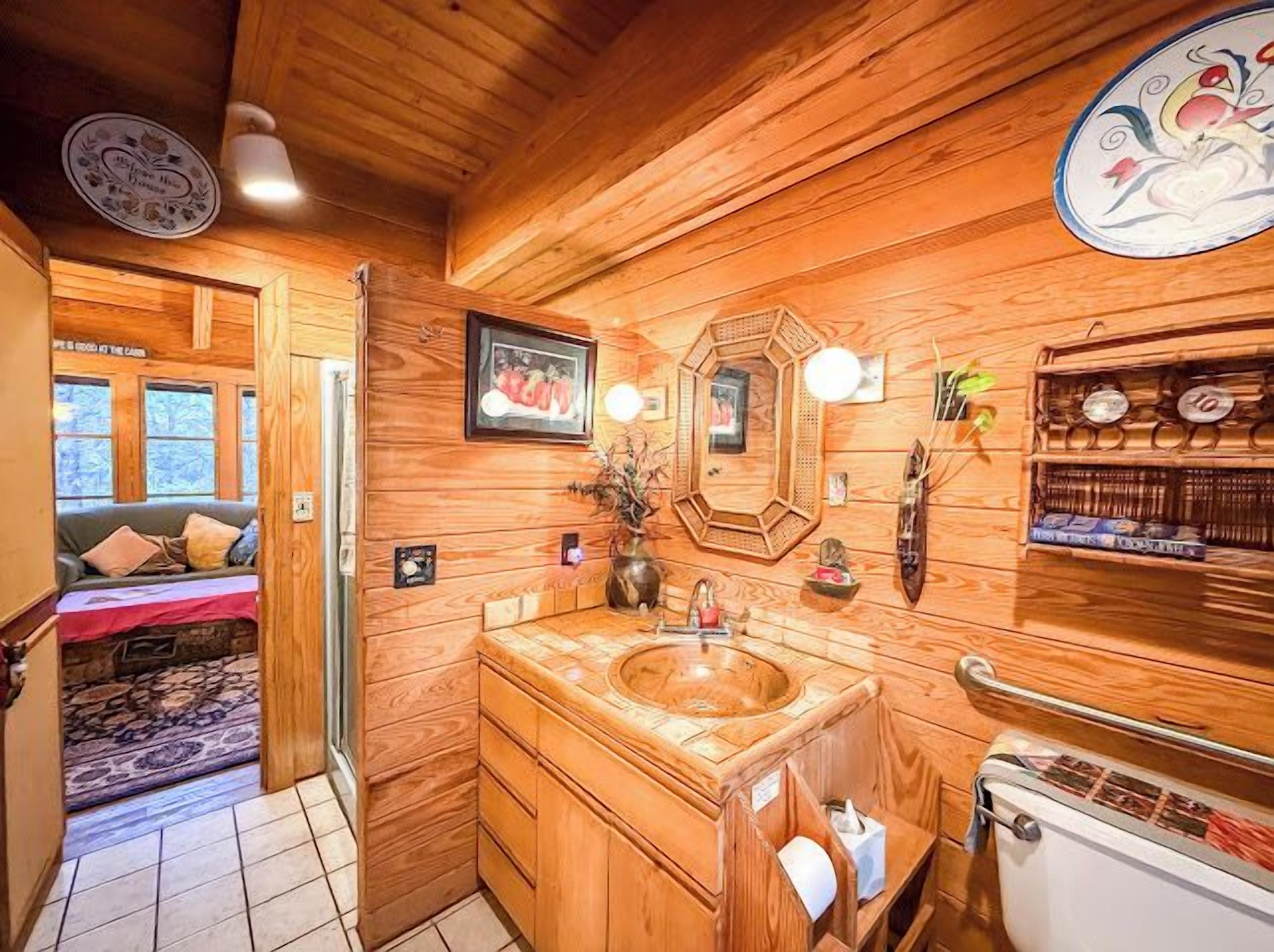 Un intérieur en bois avec un lavabo en bois, un miroir et une étagère contenant des articles de toilette.