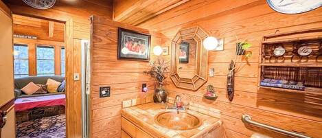 Un intérieur en bois avec un lavabo en bois, un miroir et une étagère contenant des articles de toilette.