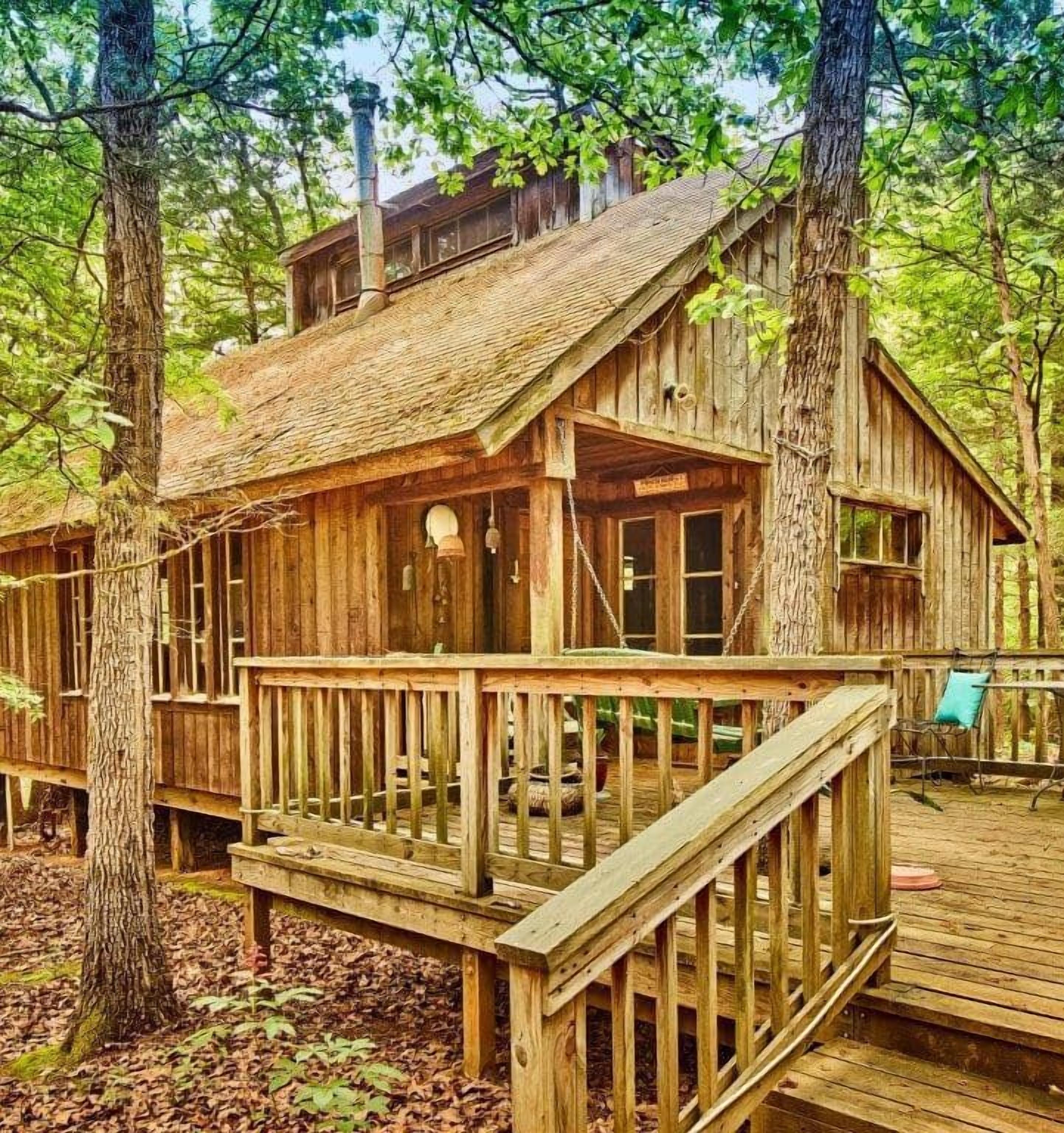 Una cabaña de madera con terraza, rodeada de árboles.
