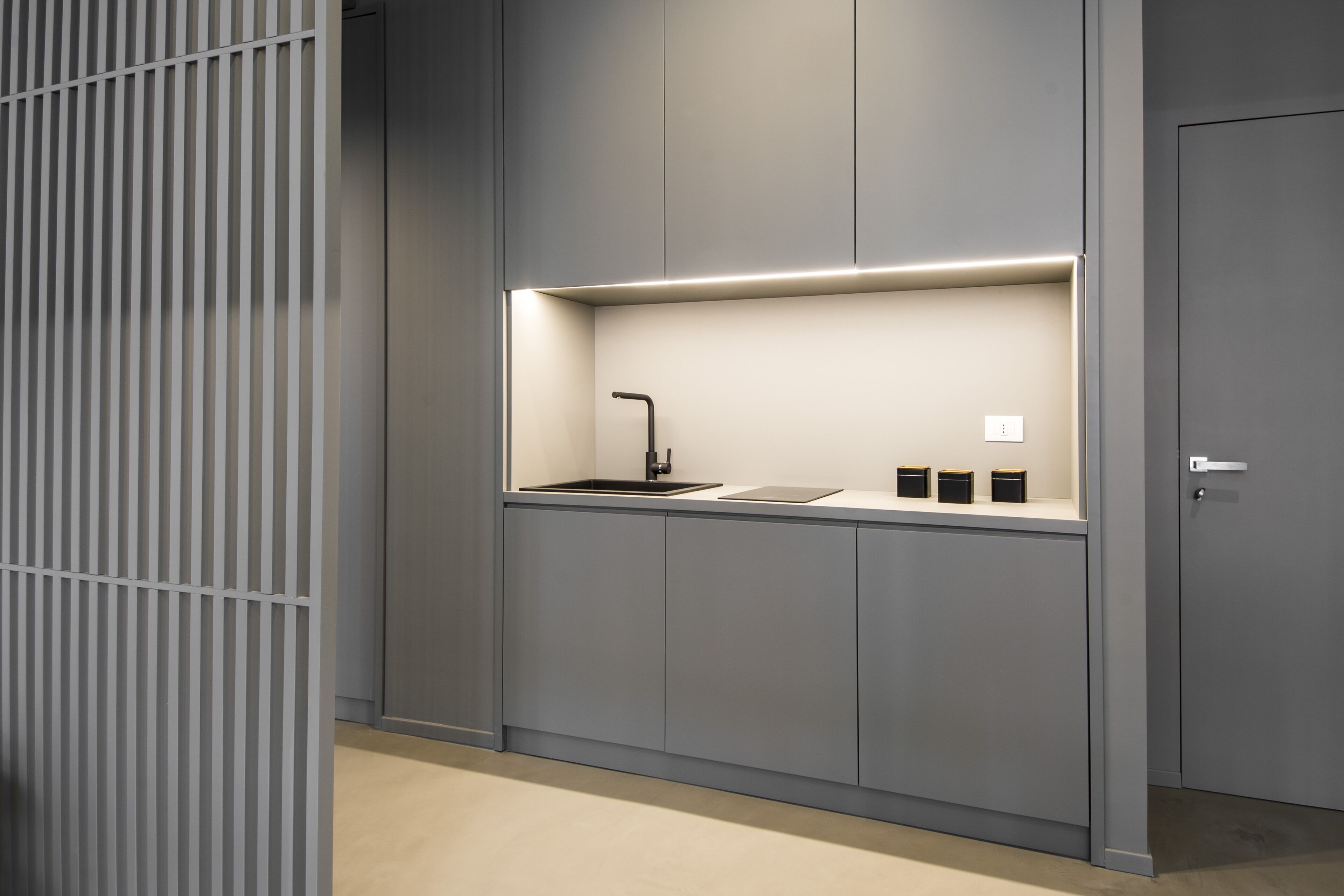 A modern kitchen with a built-in sink, a countertop, and a door to the right.
