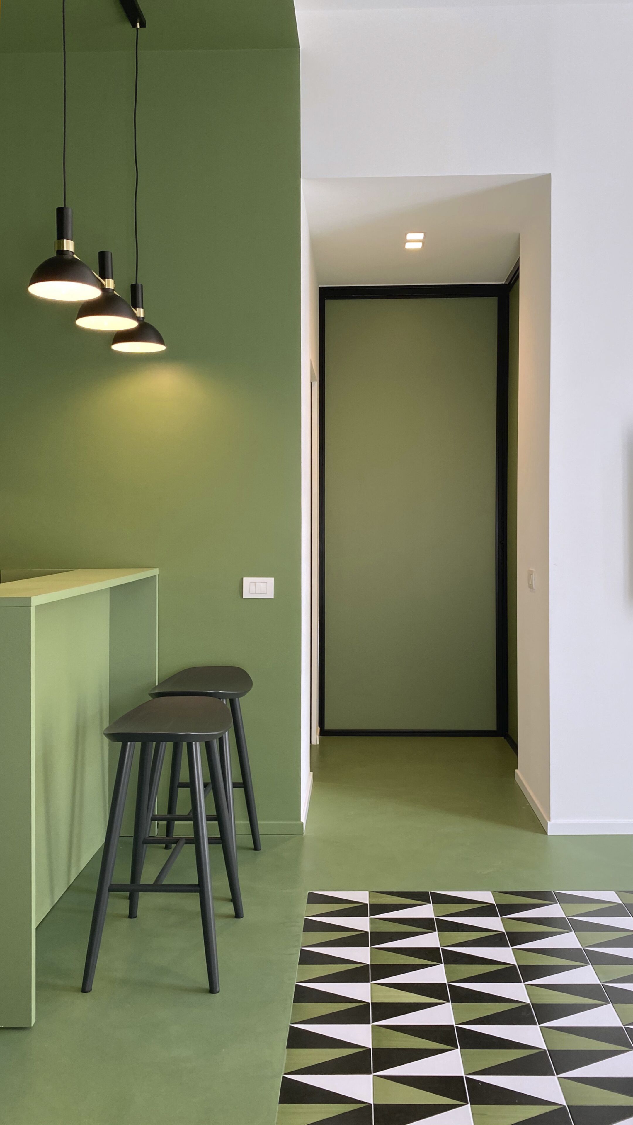 Ein modernes Interieur mit grüner Wand, Boden in Schwarz-Weiß-Muster und minimalistischem Design.