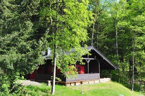 A cabin with a wooden deck, surrounded by dense forest. - Blockhaus Bodefall (Braunlage)