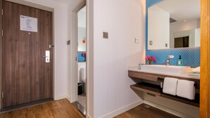 A modern bathroom with a wooden door, a sink with a mirror, and a blue tiled wall. - Holiday Inn Express Chengdu East by IHG (Chengdu)