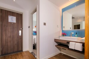A modern bathroom with a wooden door, a sink with a mirror, and a blue tiled wall. - Holiday Inn Express Chengdu East by IHG (Chengdu)