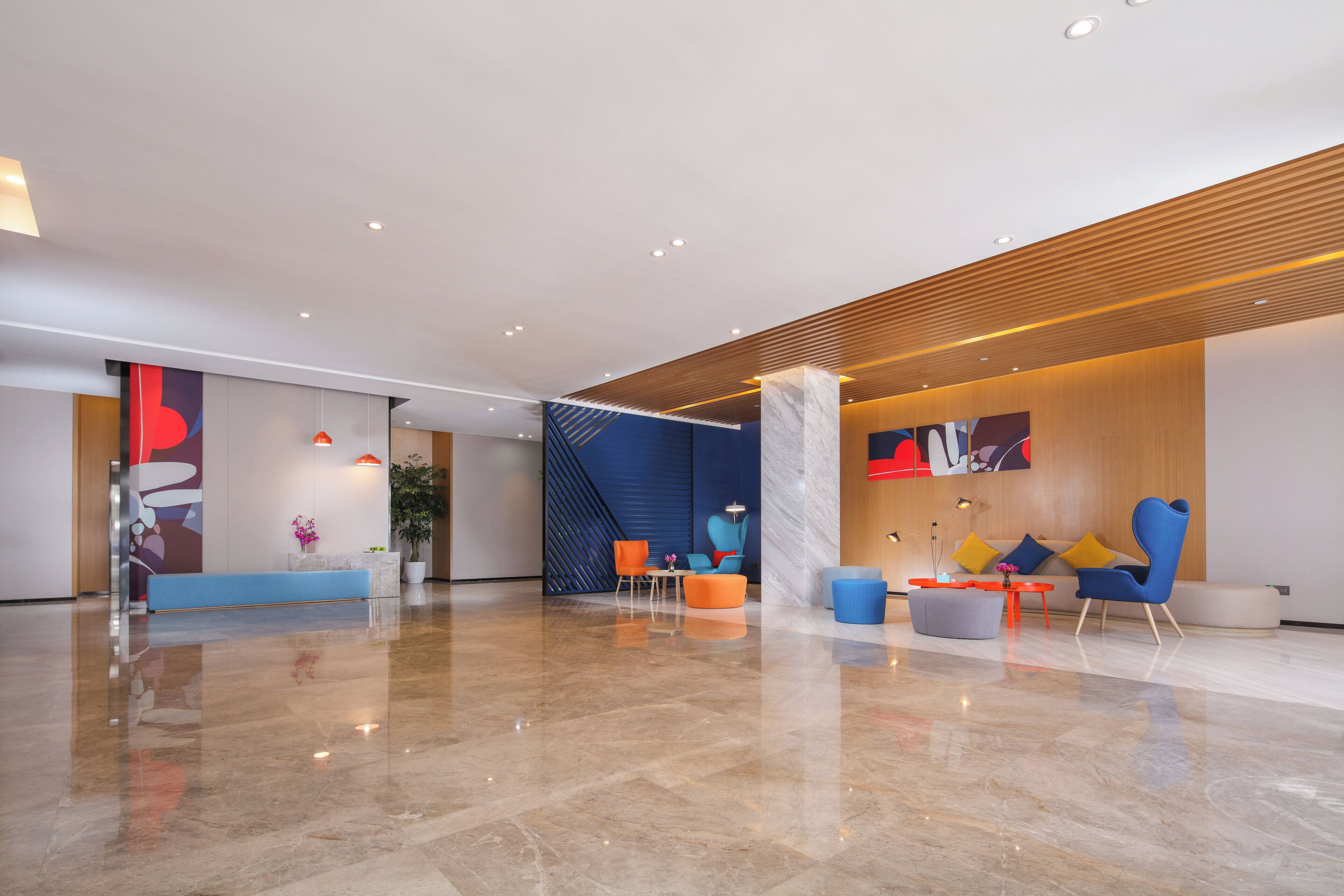 A modern lobby with a reception desk, seating area, and a wooden slatted ceiling.