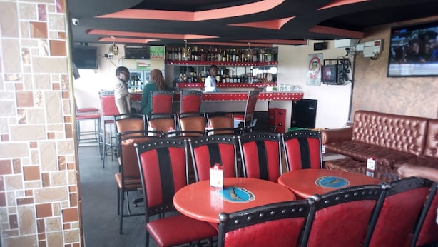 Ein Restaurantinneres mit roten und schwarzen Stühlen, einer Bar und einer braunen Ledersitzbank.