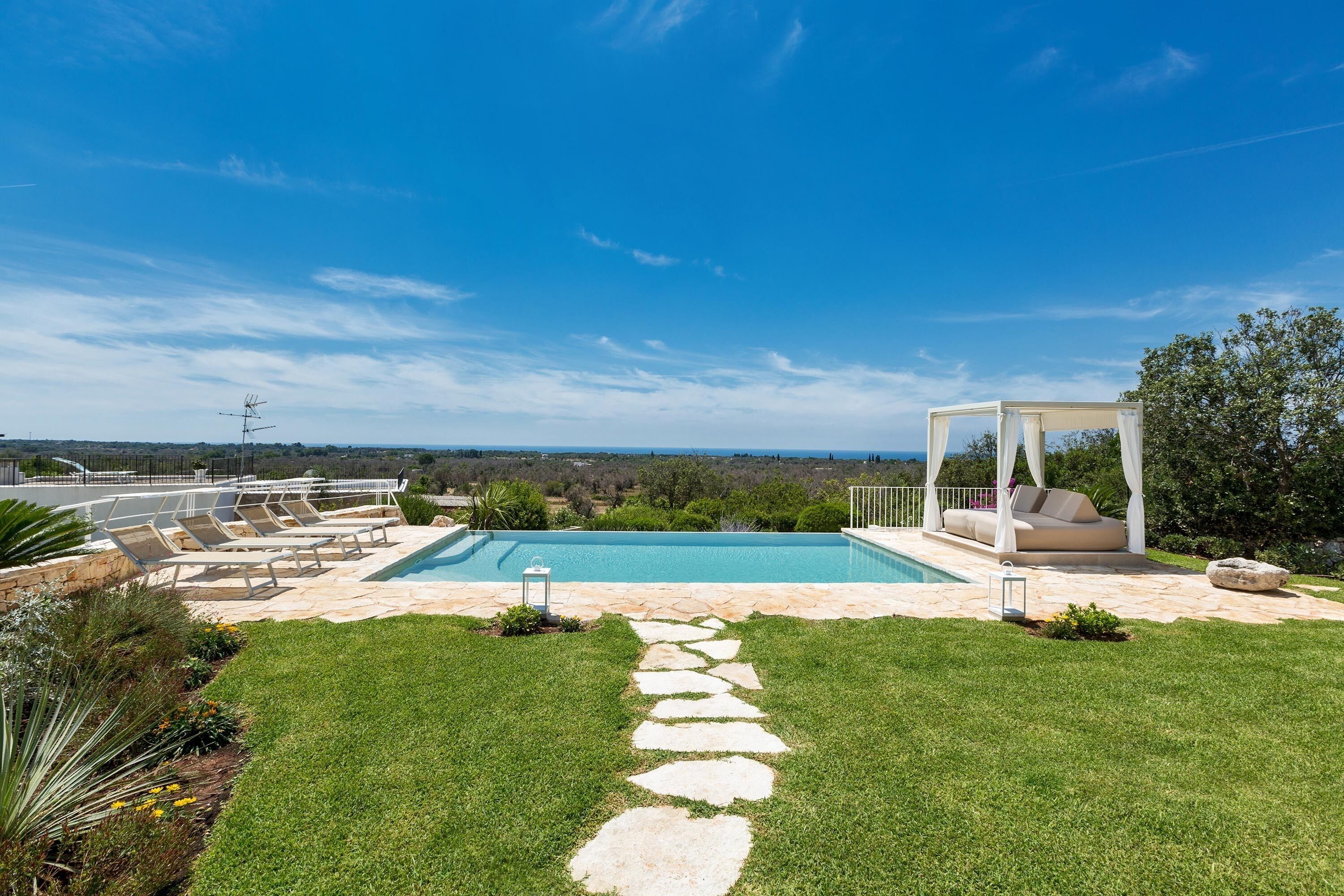 A backyard with a swimming pool, a gazebo, and a stone pathway leading to the pool.