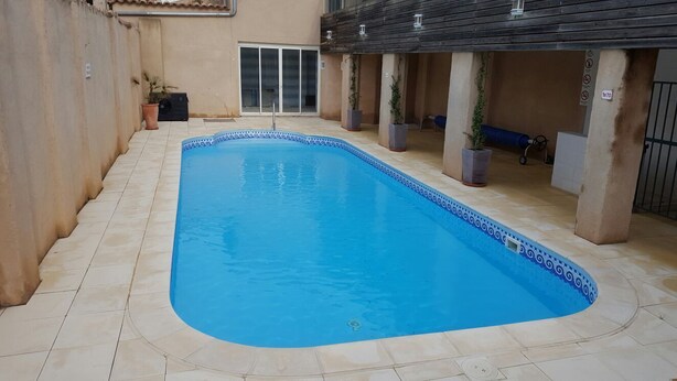 Une piscine rectangulaire bordée de carreaux, entourée d’une terrasse également carrelée.