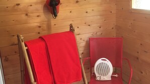 Een houten kamer met een houten trap, een rode handdoek, een rode stoel en een witte ventilator.