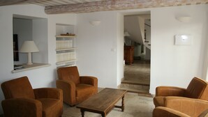 Una sala de estar con una mesa de centro de madera, dos sillones marrones y una lámpara sobre una estantería.