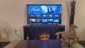 A television displaying Disney's Aladdin, with a fireplace below and a decorative horse figure to the right.