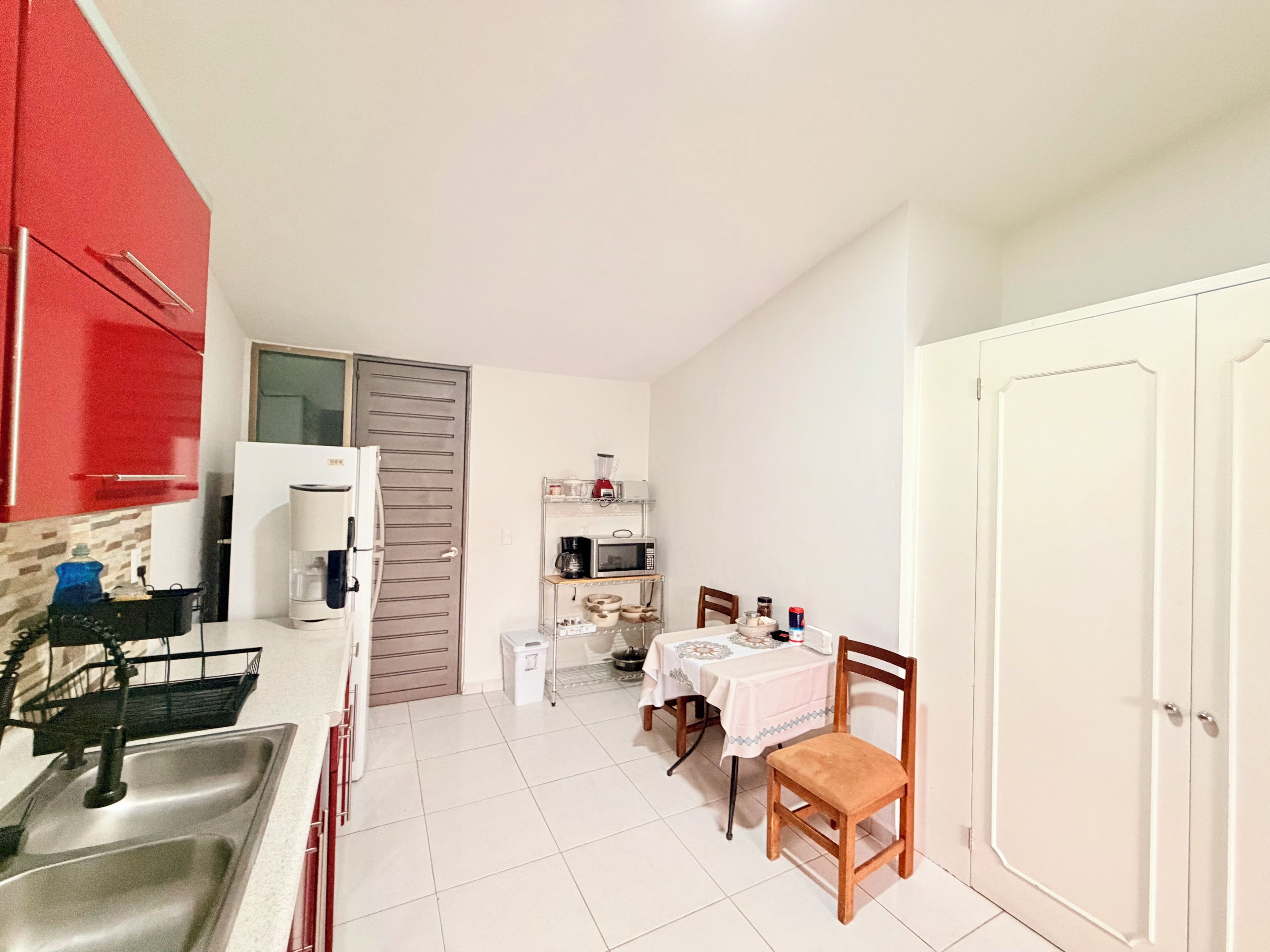 A compact kitchen with a sink, a microwave, and a dining area with a table and chairs.