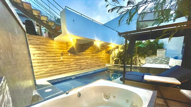 Ein moderner Poolbereich im Freien mit Whirlpool, einer Holzverkleidung und einer Sitzecke mit Tisch und Stühlen.