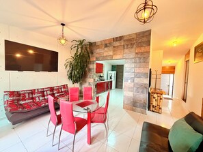 A modern living room with a glass dining table, red chairs, a sofa, and a large plant. - Loft con Alberca Climatizada/2 Exclusivos Jacuzzis Premium/Terraza/Grill/Wi-Fi (Lomas Tetela)