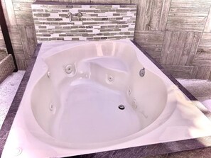 A spa tub with a stone mosaic wall behind it. - Loft con Alberca Climatizada/2 Exclusivos Jacuzzis Premium/Terraza/Grill/Wi-Fi (Lomas Tetela)