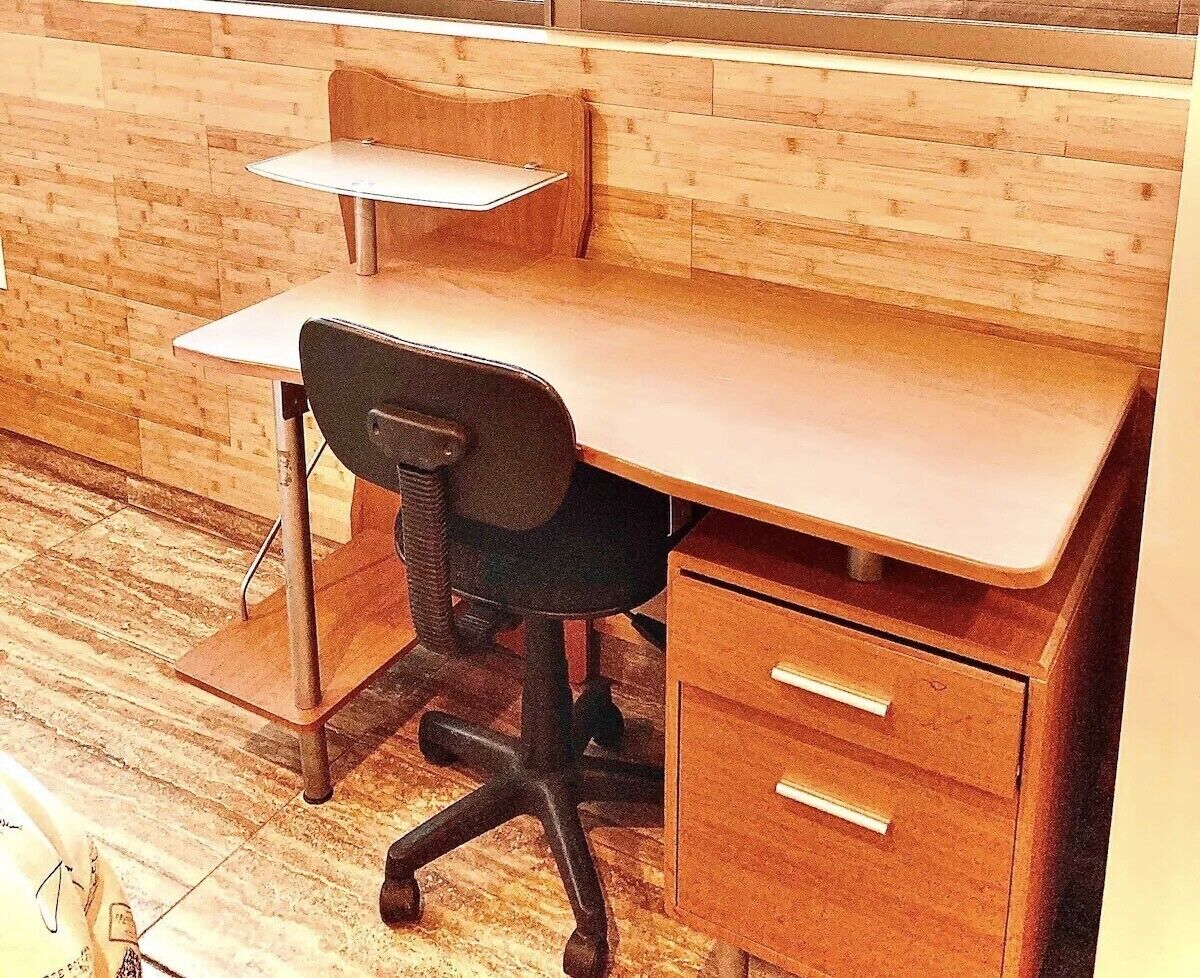 A wooden desk with a chair and a small table, accompanied by a drawer unit.