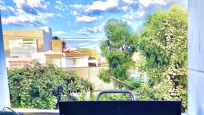 A balcony with a grill, a sink, and a view of buildings and trees. - Loft con Alberca Climatizada/2 Exclusivos Jacuzzis Premium/Terraza/Grill/Wi-Fi (Lomas Tetela)