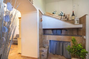 A cozy kitchen with a stone countertop, a wooden shelf, and a small plant.