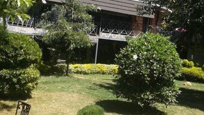 A garden with a wooden pergola, various shrubs, and a lawn. - Taidy Suites Eldama Ravine (Eldama Ravine)