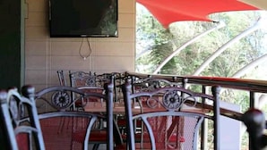 A restaurant with outdoor seating, a television mounted on the wall, and a red canopy providing shade. - Taidy Suites Eldama Ravine (Eldama Ravine)