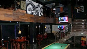A billiards table in a dimly lit room with wooden furniture and a large motorcycle mural on the wall. - Taidy Suites Eldama Ravine (Eldama Ravine)