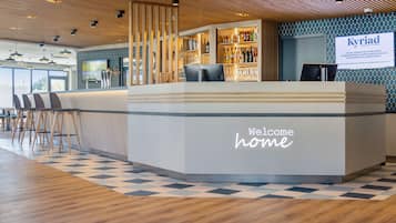 A modern hotel reception area with a check-in counter, bar, and seating area.