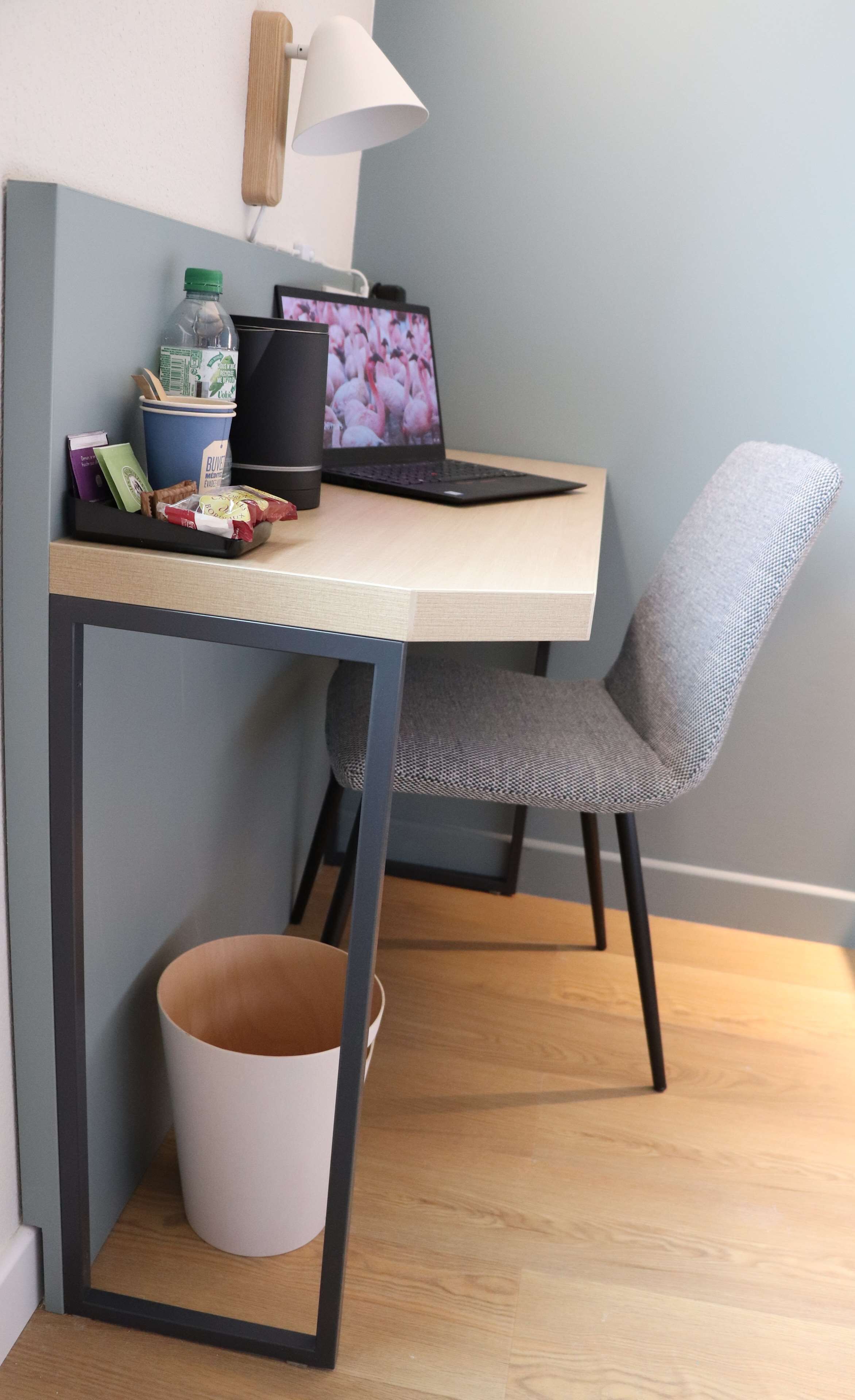 Un'area dedicata al lavoro, con scrivania, sedia, portatile e cestino.