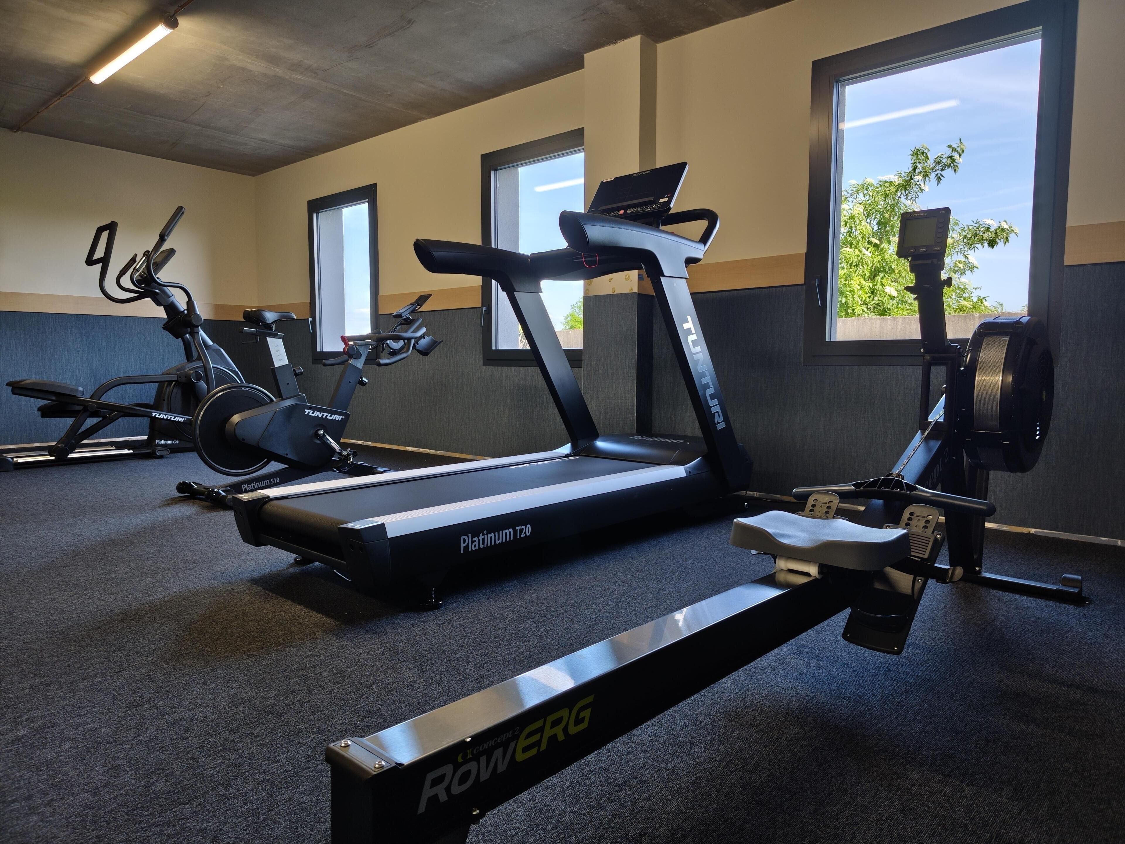 Ein Fitnessstudio mit Laufbändern, Ergometer und Rudergeräten.