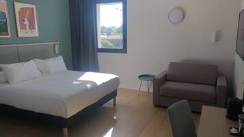 Een hotelkamer met een bed, een bank, een klein tafeltje en een raam met uitzicht.