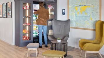 A man interacting with a vending machine in a modern interior with a map on the wall and stylish seating.