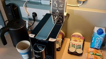 Una màquina de cafè, una làmpada i diversos aliments sobre una taula.