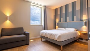 Un dormitorio moderno con una cama, lámparas de noche, un sofá y una ventana con cortinas.