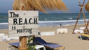 A beach sign with the text "The BEACH is waiting" and beach chairs in the background. - Bungalow on vacation park near the beach Noordwijk (Noordwijkerhout)