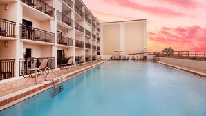 Een meerlaags hotel met een zwembad, balkons en ligbedden.