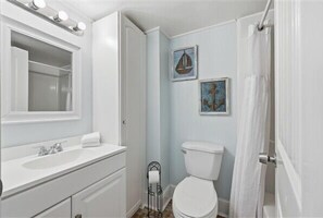 A bathroom with a white vanity, a toilet, and two framed artworks on the wall. - Beacher's Oceanfront Balcony, Condo Complex Construction 10/2026-1/2027 (St. Augustine)