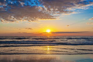 Ein Strand mit Wellen und einem Sonnenuntergang.