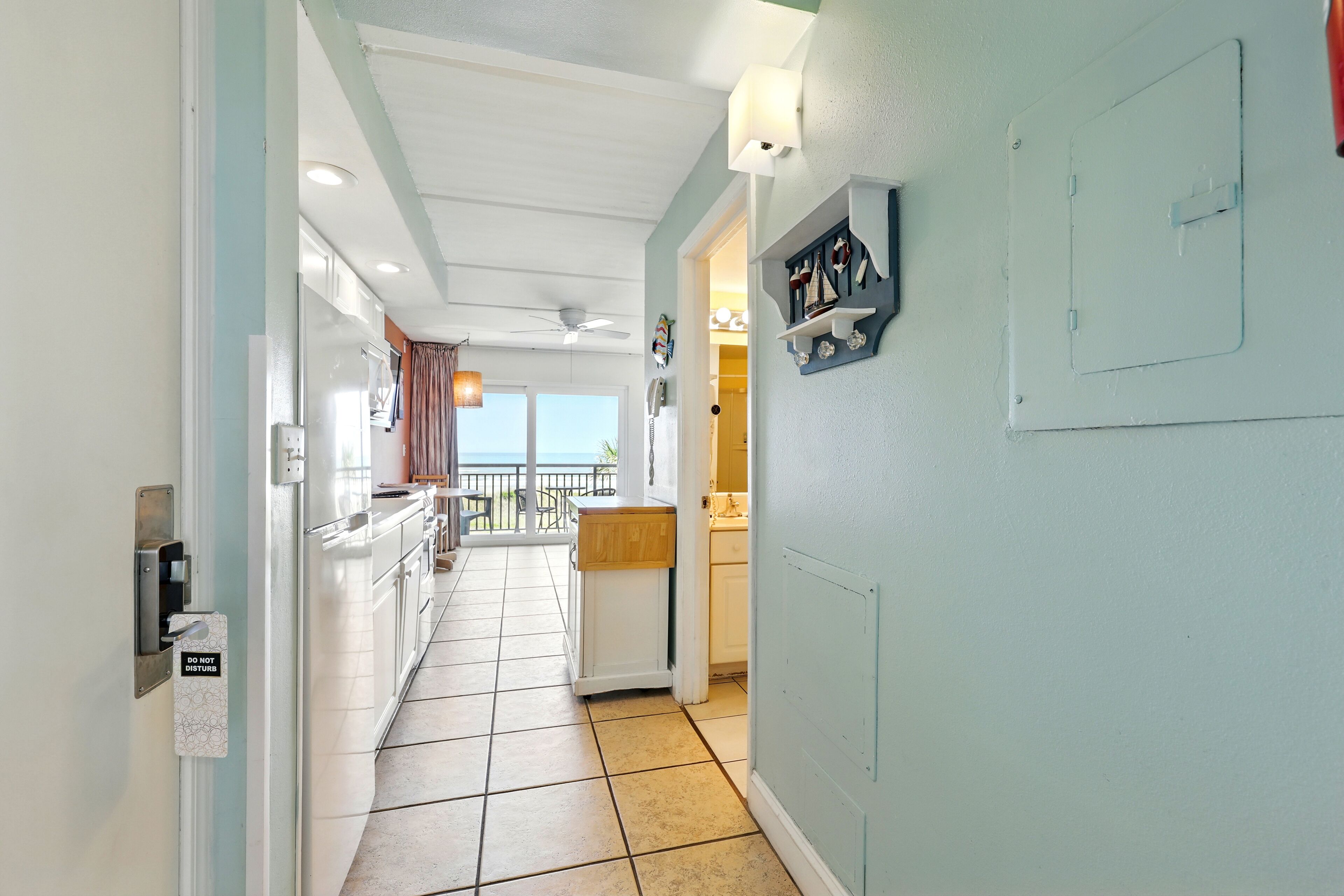 A corridor leading to a kitchen with a view of the sea.