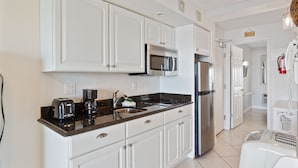 A kitchen with white cabinets, stainless steel appliances, a coffee maker, and a toaster. - Beacher's Oceanfront Balcony Suite with onsite Front Desk and Staff (St. Augustine)