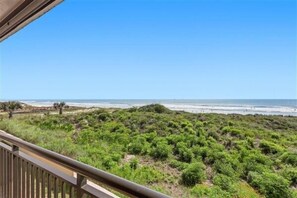 A balcony with a view of the beach and dunes.