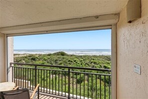 A balcony with a view of the beach and ocean.