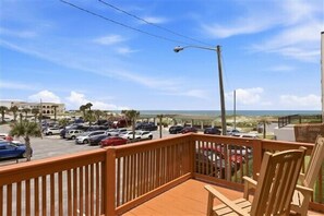 A balcony with a view of a parking lot and beach.