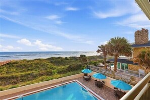 A pool area with a view of the ocean, outdoor seating, and a stone building. - Beacher's Oceanfront Balcony, Condo Complex Construction 10/2026-1/2027 (St. Augustine)