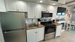 A modern kitchen with white cabinets, stainless steel appliances, and a wooden countertop. - Best Location at Beacher's Lodge - King Bed - Perfect View! (St. Augustine)