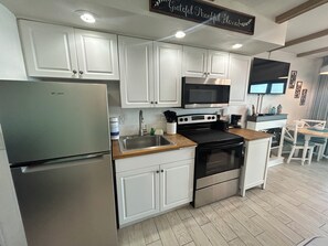 A modern kitchen with white cabinets, stainless steel appliances, and a wooden countertop. - Best Location at Beacher's Lodge - King Bed - Perfect View! (St. Augustine)