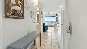 Een gang met een bank, een houten wanddecoratie en uitzicht op een balkon.